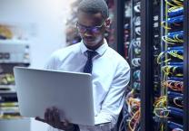 Man using a laptop next to wire tower